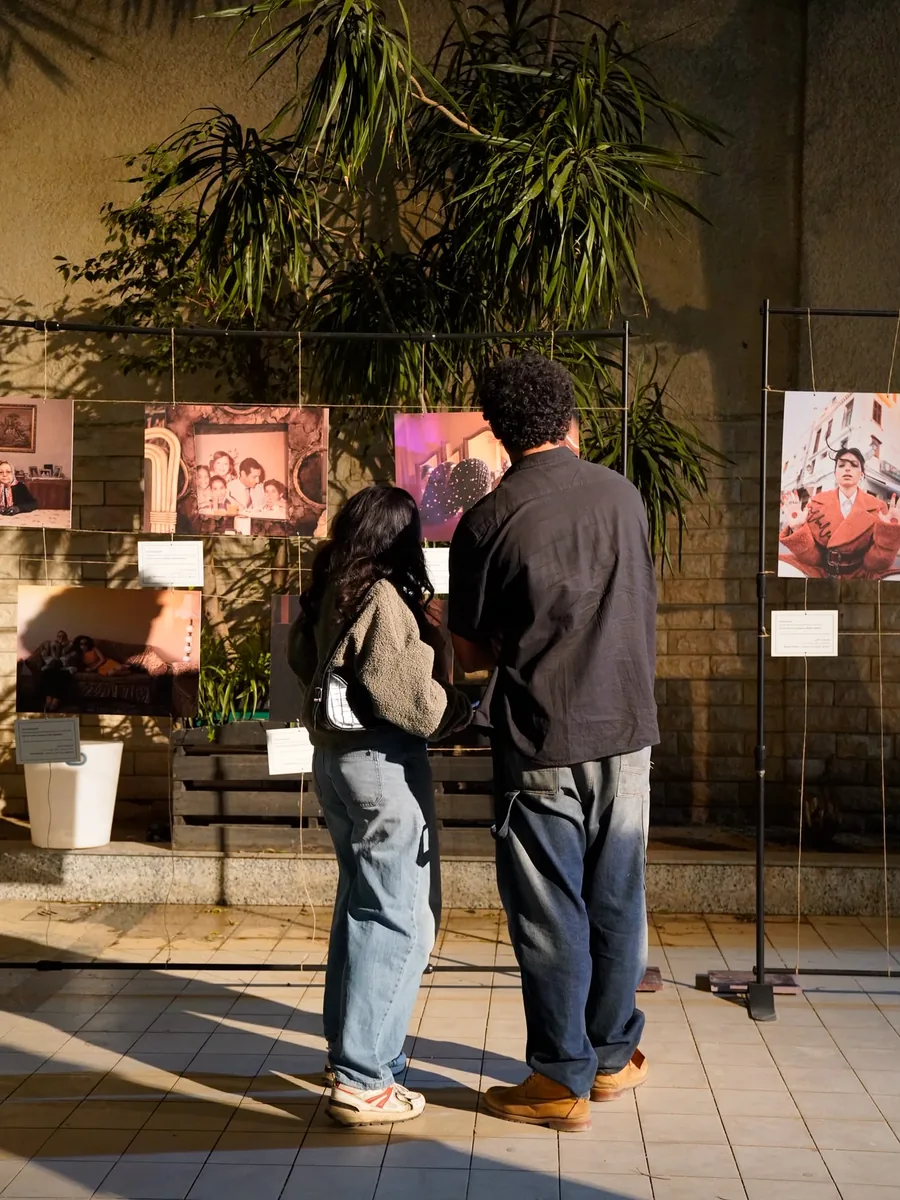 Deux visiteurs regardent des photographies accrochées dans la cour.